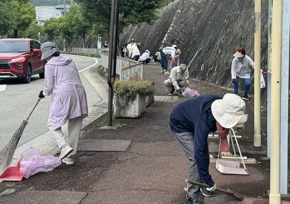 4丁目バス停前を掃除する人々