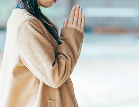 女性が神前で合掌して一心に願い事をしている